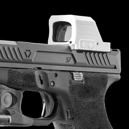 A close-up studio shot of a handgun with a white opticgard cover for holosun 507c X3 against a solid black background. [ads-hide]