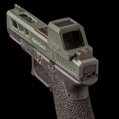 A semi-automatic handgun with an OpticGard Cover for Holosun 507CX3 on top, shown against a solid black background. [ads-hide]