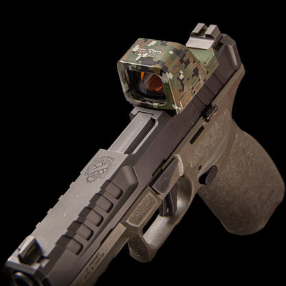 A semi-automatic handgun in matte dark gray with a digital camouflage red dot sight mounted on top, photographed against a solid black background. [ads-hide]